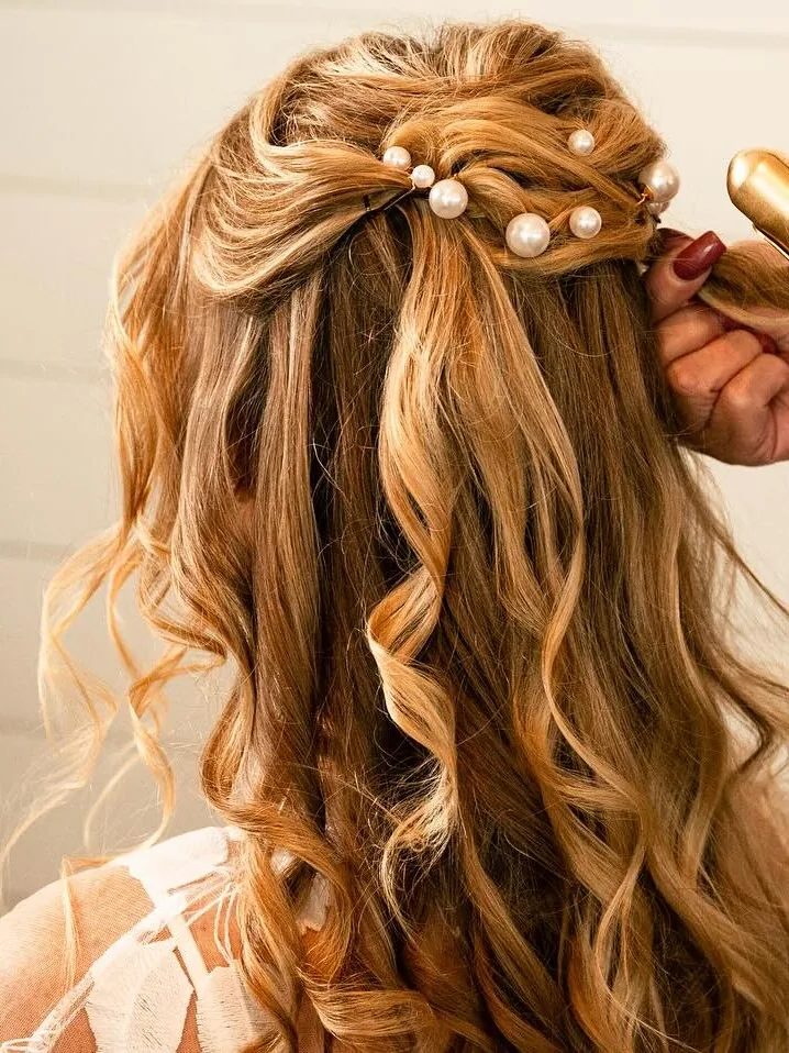Half-up bridal style with pearl pins and soft curls being set with a curling iron at Jacqui's Design Group, Arlington MA