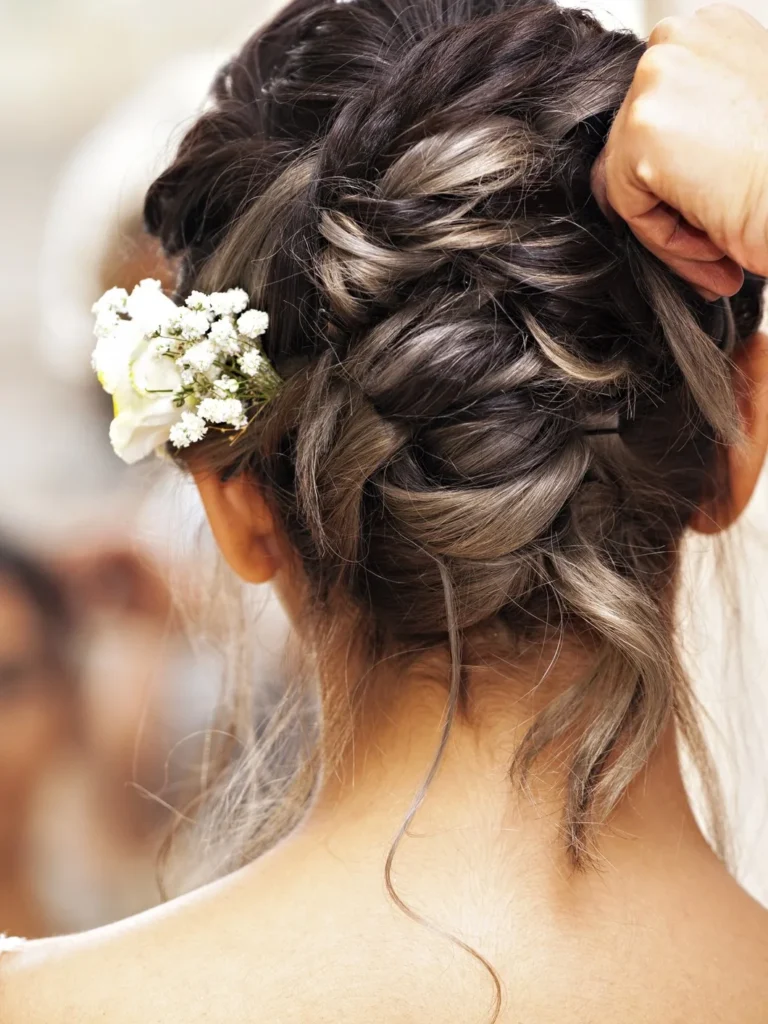 Bridal braided updo with fresh flowers being finished by a stylist at Jacqui's Design Group in Arlington, MA
